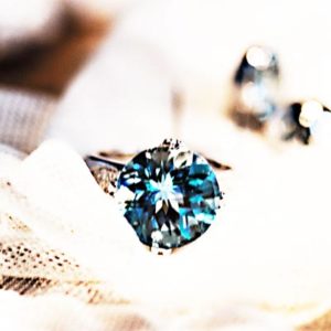 gorgeous sapphire solitaire ring artistically placed on lace with an antique sepia effect added the the photo