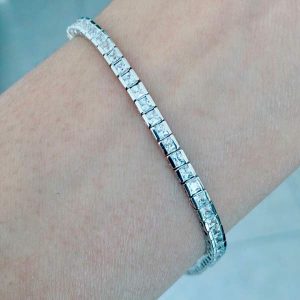 modern tennis bracelet with desert diamond simulants of size 2.5 millimeter square princess cut with a semibezel setting pictured on a woman's wrist